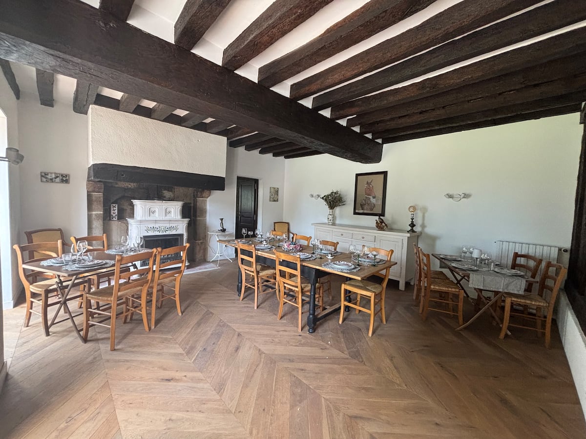Salle à manger à poutres apparentes et cheminée