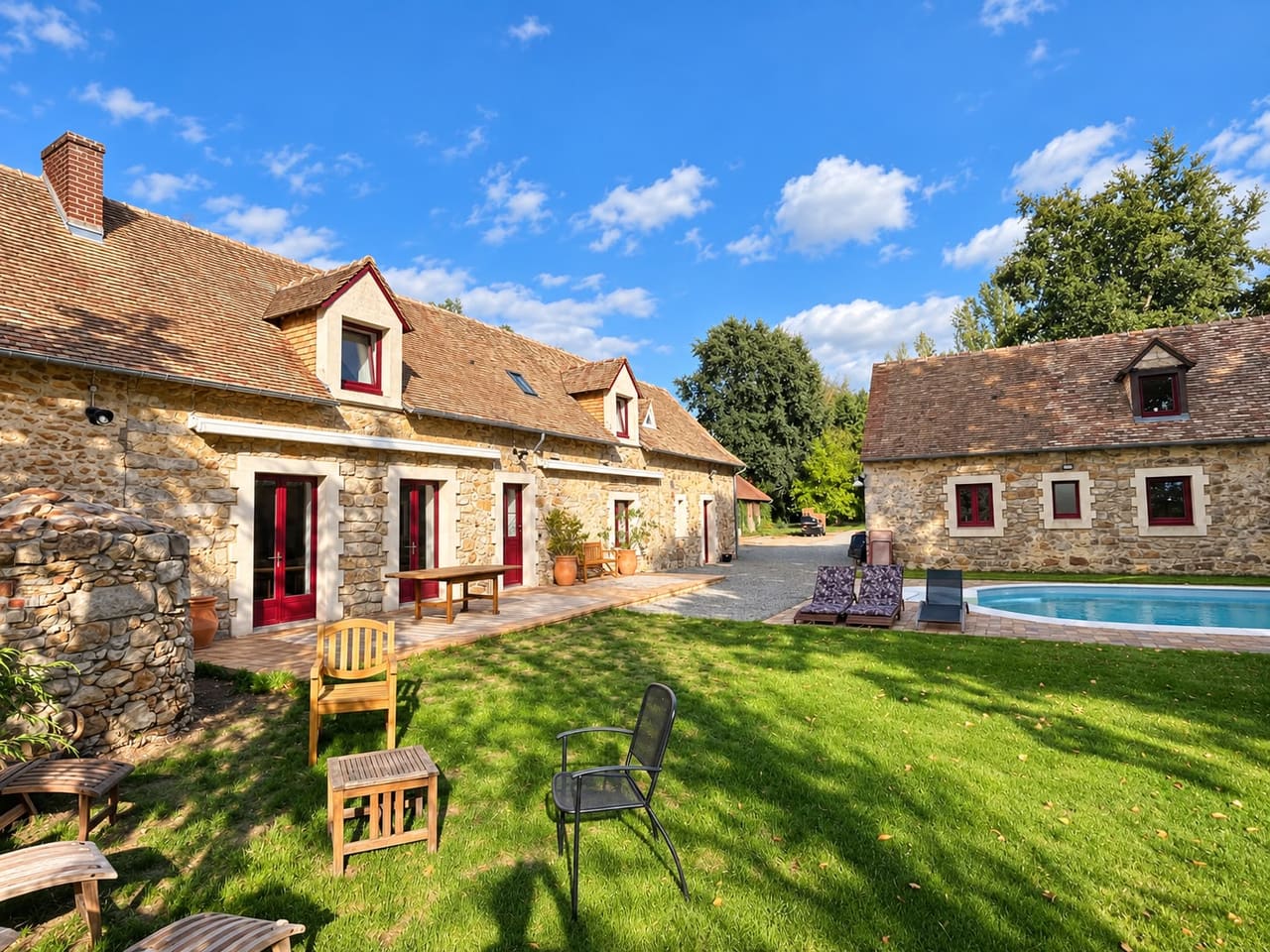 La cour du domaine, ses deux corps de bâtiment en pierre et la piscine