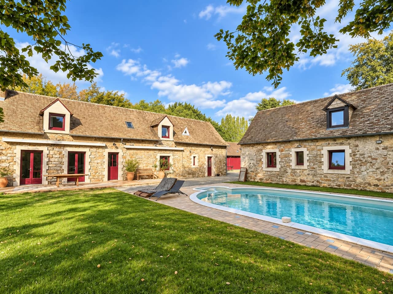 La piscine chauffée et le jardin, encadrés par les deux corps de bâtiment en pierre